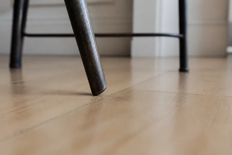Un pied de chaise en métal dans une habitation française présente un patin manquant, une petite imperfection affectant l'expérience client.