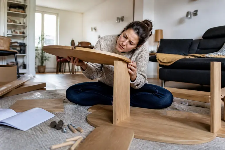 Femme de 30 ans à Lyon tentant d'assembler une table basse Sklum, visiblement contrariée.