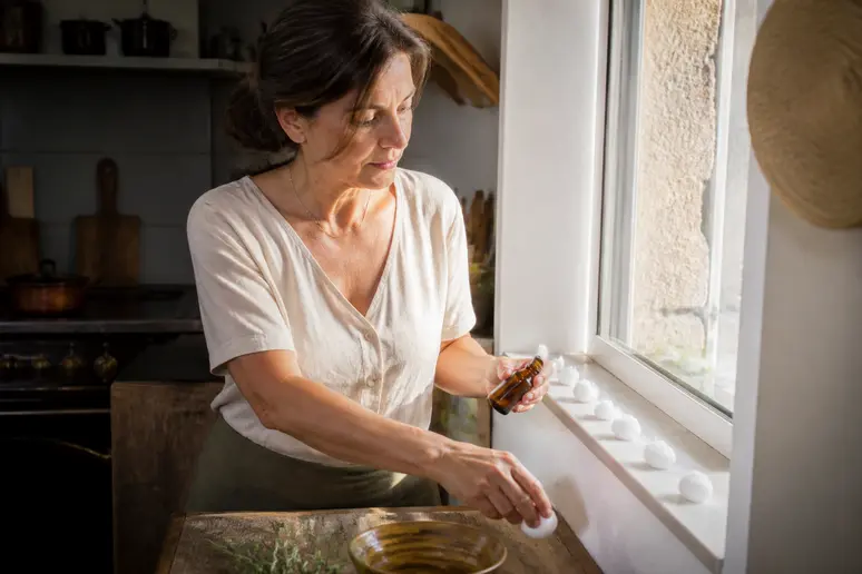 Comment éliminer les rats: femme plaçant des répulsifs naturels à base d'huiles essentielles dans une cuisine.