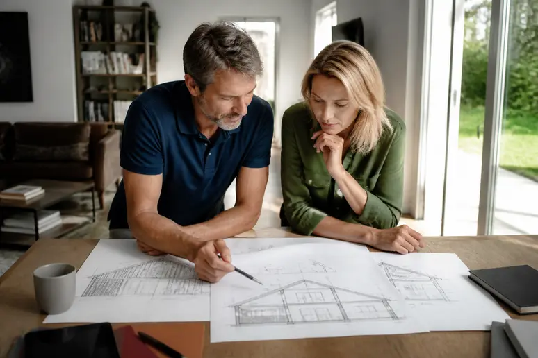 Couple français étudiant les plans d'un projet d'amenagement sous pente.