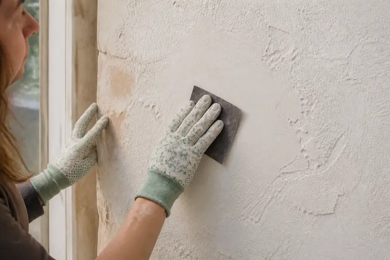 Finitions pour reboucher un trou dans un mur : ponçage méticuleux d'une zone réparée.