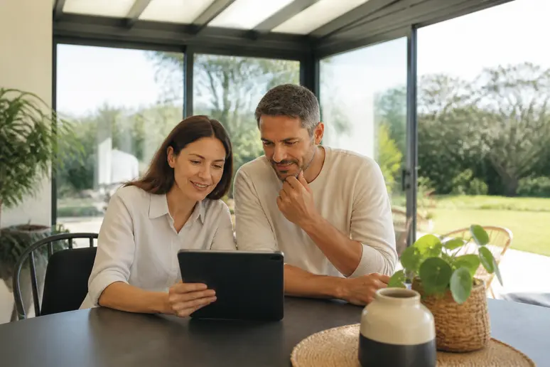 Couple français étudiant un devis pour le budget d'une veranda moderne de 20m².